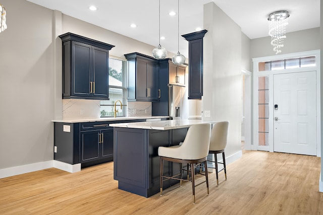 kitchen featuring hanging light fixtures, an inviting chandelier, a kitchen breakfast bar, light hardwood / wood-style flooring, and kitchen peninsula