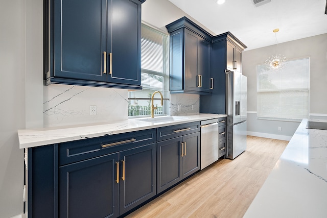 kitchen with sink, decorative backsplash, light wood-type flooring, blue cabinetry, and appliances with stainless steel finishes