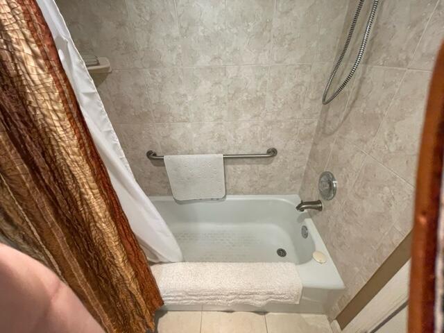 bathroom with tile patterned floors and shower / bath combo with shower curtain