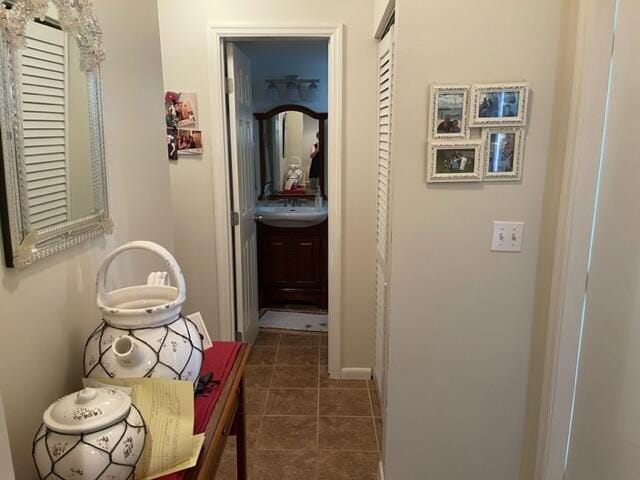 corridor with dark tile patterned flooring and a sink