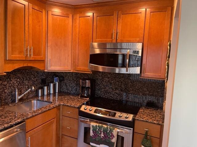 kitchen with backsplash, dark stone countertops, sink, and appliances with stainless steel finishes