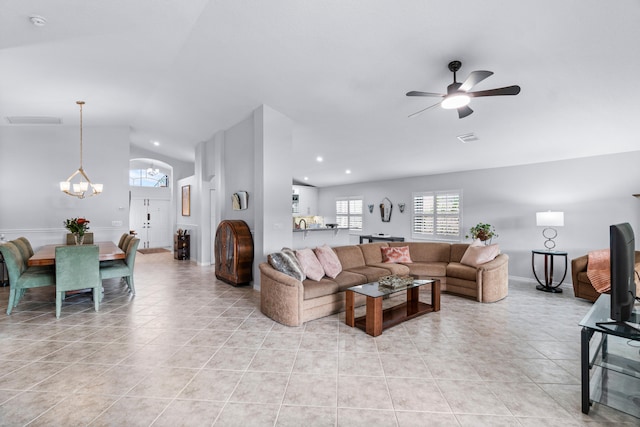 tiled living room featuring ceiling fan with notable chandelier, a healthy amount of sunlight, and lofted ceiling