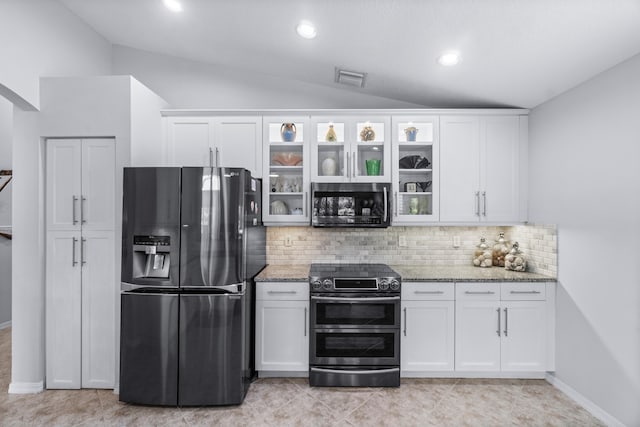 kitchen with white cabinetry, light stone countertops, vaulted ceiling, and appliances with stainless steel finishes