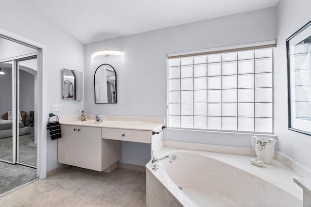 bathroom featuring tile patterned flooring, vanity, and a bath