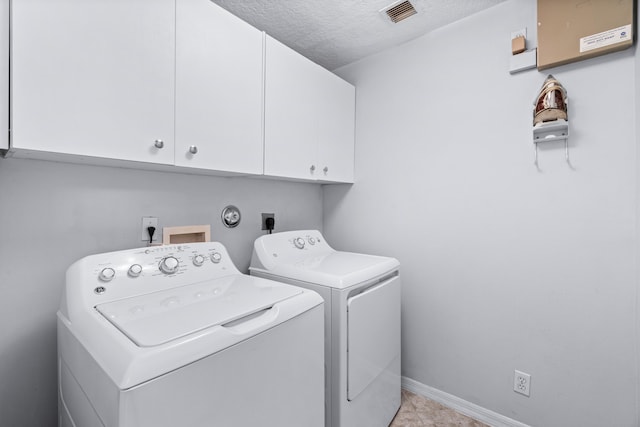 washroom with cabinets, a textured ceiling, and washing machine and clothes dryer