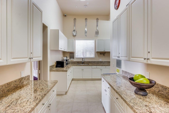 kitchen with white cabinetry, sink, light tile patterned flooring, and light stone counters