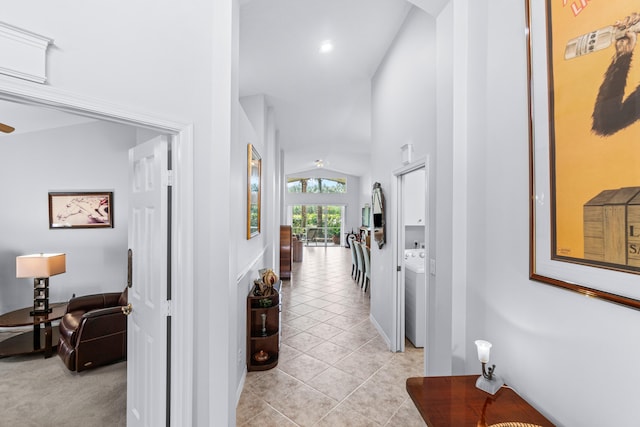 hallway featuring light tile patterned floors, lofted ceiling, and washer / clothes dryer