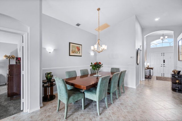 tiled dining area with high vaulted ceiling and an inviting chandelier