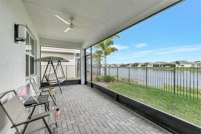 unfurnished sunroom featuring ceiling fan and a water view