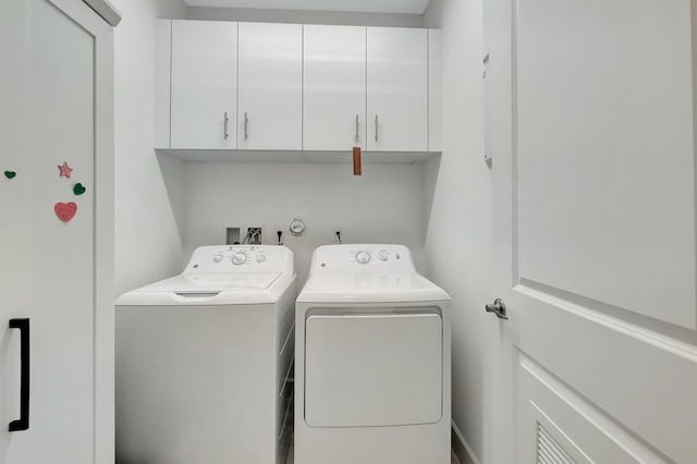 clothes washing area with washer and clothes dryer and cabinets