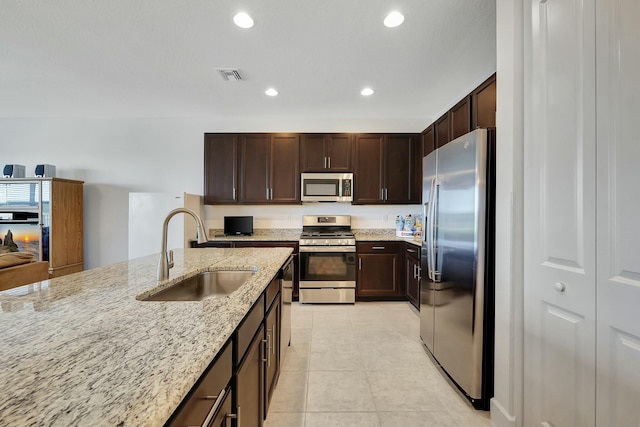 kitchen featuring light stone counters, sink, light tile patterned floors, and appliances with stainless steel finishes