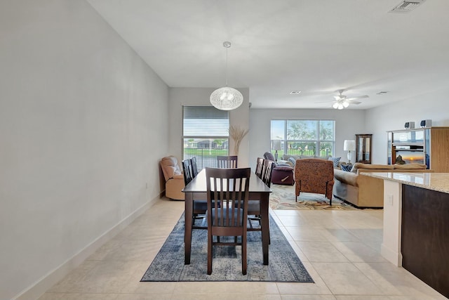 tiled dining room featuring ceiling fan with notable chandelier