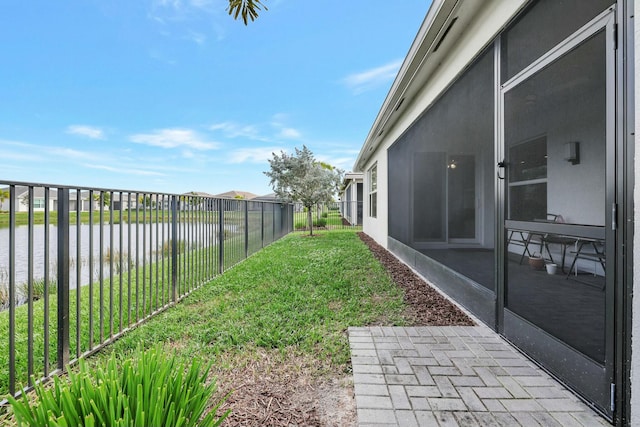 view of yard with a sunroom and a water view