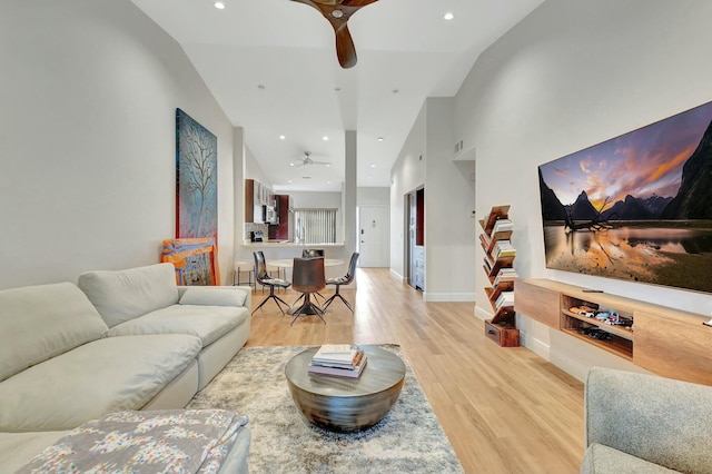 living room featuring ceiling fan, light hardwood / wood-style flooring, and high vaulted ceiling