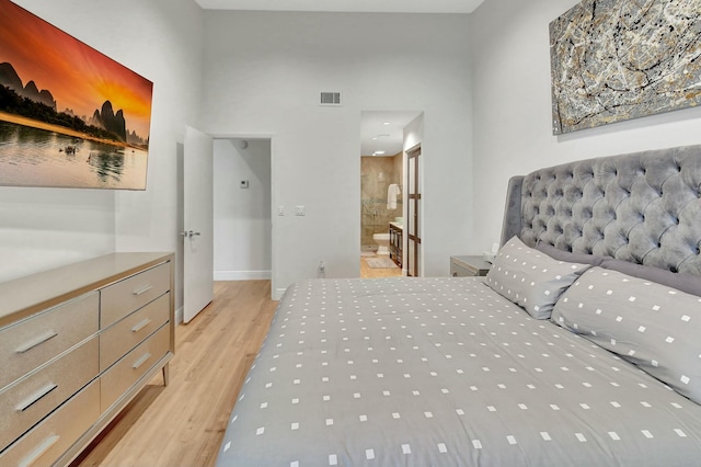 bedroom with ensuite bathroom and light hardwood / wood-style floors