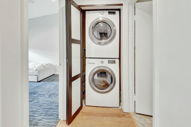 laundry area with stacked washer / drying machine and light wood-type flooring