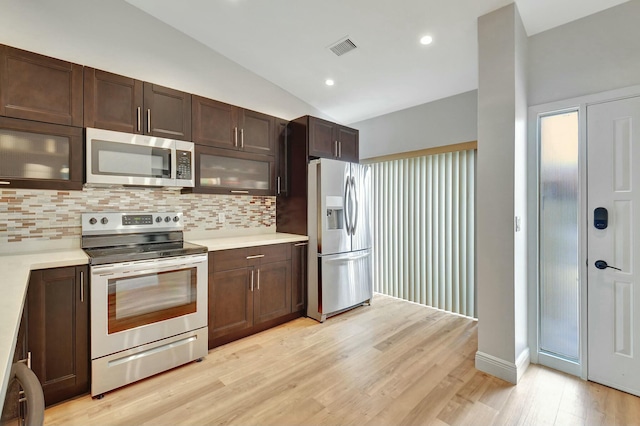 kitchen featuring lofted ceiling, backsplash, light hardwood / wood-style floors, dark brown cabinetry, and stainless steel appliances