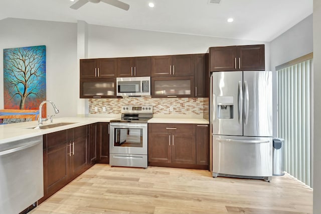 kitchen featuring sink, light hardwood / wood-style flooring, vaulted ceiling, decorative backsplash, and stainless steel appliances