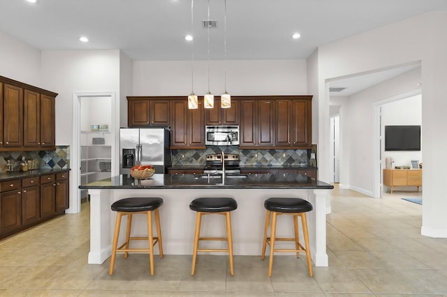 kitchen featuring decorative backsplash, stainless steel appliances, and a center island with sink