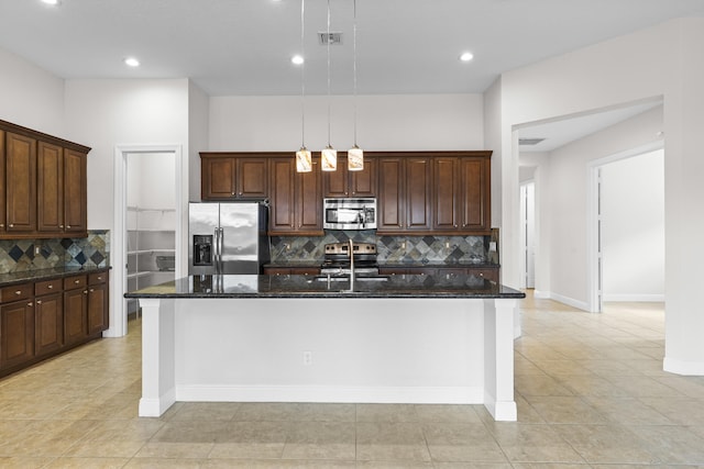 kitchen featuring decorative light fixtures, decorative backsplash, stainless steel appliances, and an island with sink