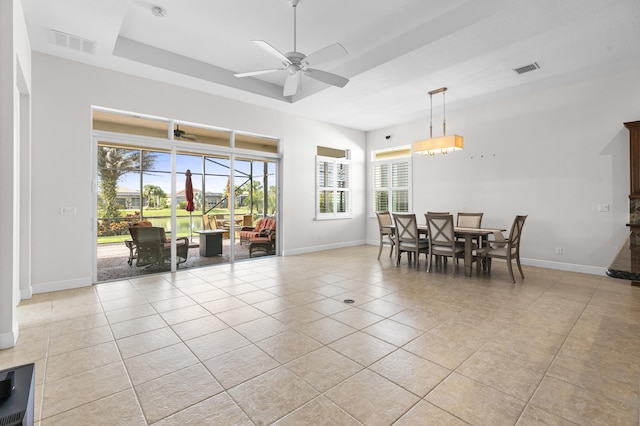 tiled dining room featuring ceiling fan and a raised ceiling