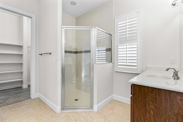 bathroom featuring tile patterned floors, a shower with door, and vanity