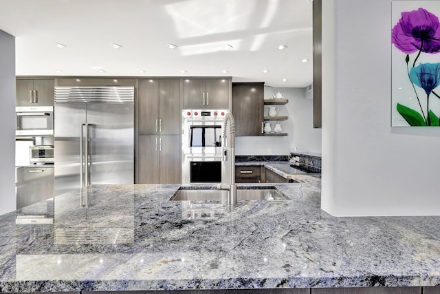 kitchen with stone countertops, sink, dark brown cabinets, and stainless steel appliances