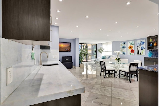 kitchen featuring dark brown cabinetry, light stone countertops, and sink