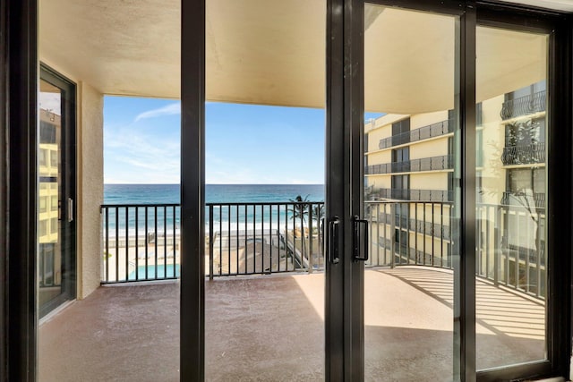 balcony featuring a view of the beach and a water view