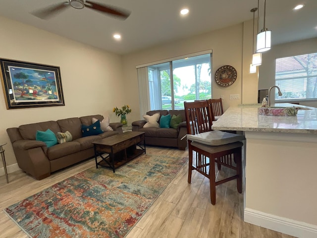 living room with ceiling fan and light hardwood / wood-style flooring