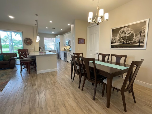 dining space featuring light hardwood / wood-style floors, an inviting chandelier, and sink