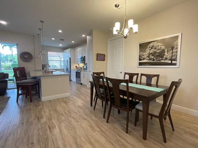 dining space featuring light hardwood / wood-style floors, sink, and an inviting chandelier