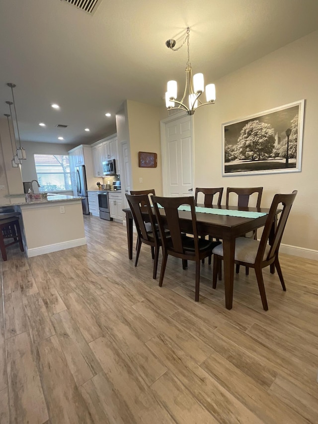 dining room featuring light wood-type flooring and an inviting chandelier