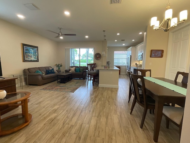 dining area featuring ceiling fan with notable chandelier and light wood-type flooring