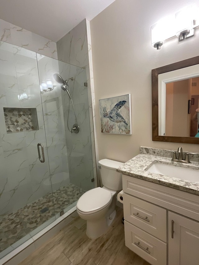 bathroom featuring hardwood / wood-style floors, vanity, toilet, and a shower with shower door