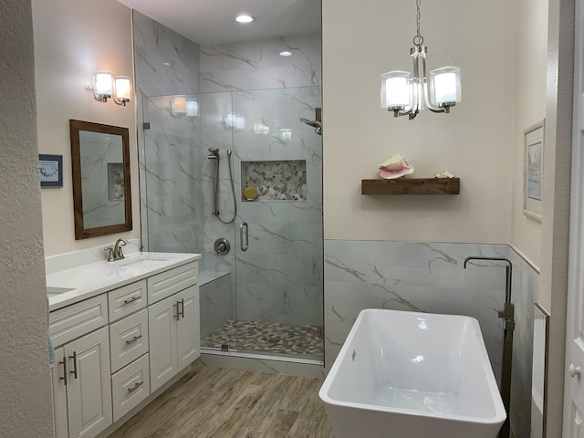 bathroom featuring a chandelier, shower with separate bathtub, vanity, tile walls, and hardwood / wood-style flooring