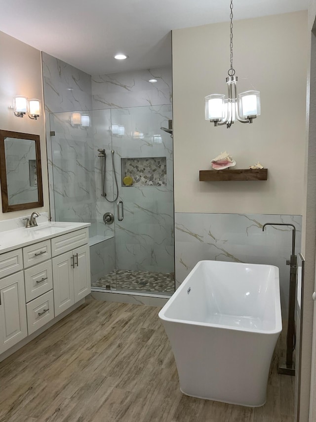 bathroom featuring vanity, shower with separate bathtub, tile walls, a notable chandelier, and hardwood / wood-style floors