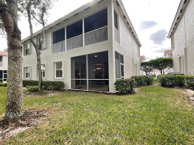 rear view of property with a sunroom and a yard