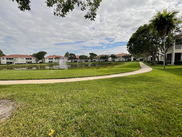 surrounding community with a water view and a lawn