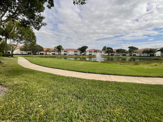 view of home's community with a water view and a yard