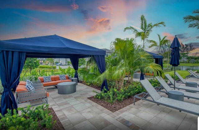 patio terrace at dusk featuring a gazebo and an outdoor living space