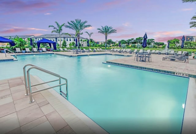 pool at dusk with a patio area