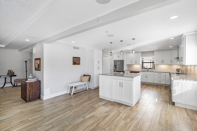 kitchen featuring pendant lighting, white cabinets, stainless steel fridge with ice dispenser, light hardwood / wood-style floors, and a kitchen island