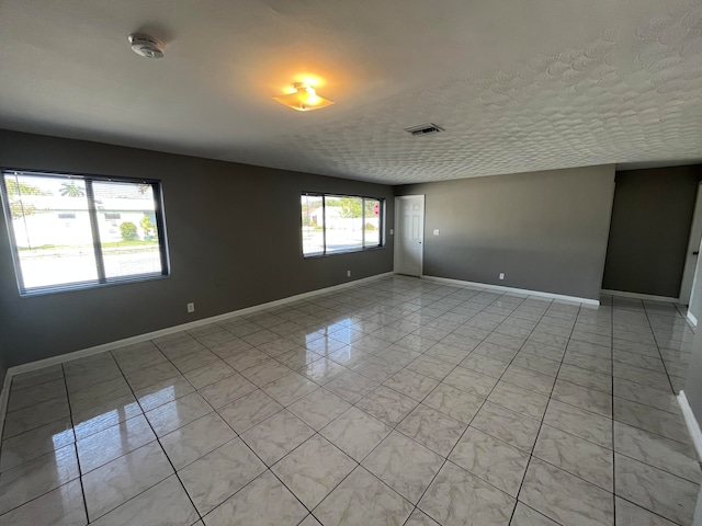 empty room featuring light tile patterned floors and a textured ceiling