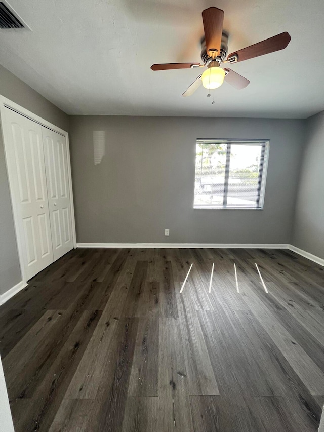 unfurnished bedroom featuring ceiling fan, dark hardwood / wood-style flooring, and a closet