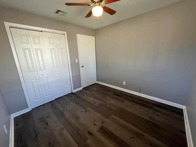 unfurnished bedroom with ceiling fan, a closet, and dark wood-type flooring