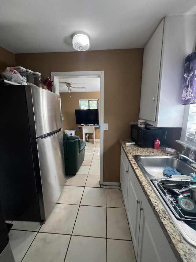 kitchen featuring white cabinetry, sink, ceiling fan, stainless steel fridge, and light tile patterned floors