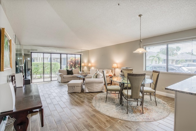 living room with a textured ceiling, light wood-type flooring, and a wealth of natural light