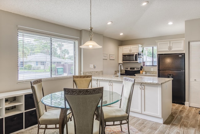 kitchen featuring pendant lighting, white cabinets, light hardwood / wood-style flooring, a textured ceiling, and appliances with stainless steel finishes