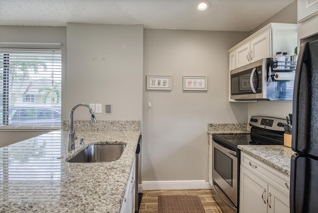 kitchen featuring light stone countertops, sink, white cabinets, and stainless steel appliances